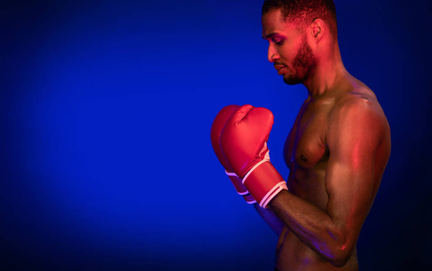 African Boxer Guy Wearing Gloves Posing On Blue Studio Background - Фото, зображення