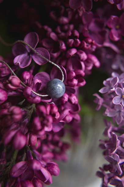Original collar de joyería de plata de piedra natural con flores de color lila violeta sobre pluma de avestruz blanco. Concepto de regalo. Accesorios de plata. Simular el espacio para el texto
. - Foto, imagen