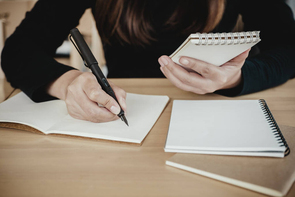 Kafede otururken elinde tuttuğu ve yazdığı bir not defteri olan yeşil bir kadın. - Fotoğraf, Görsel