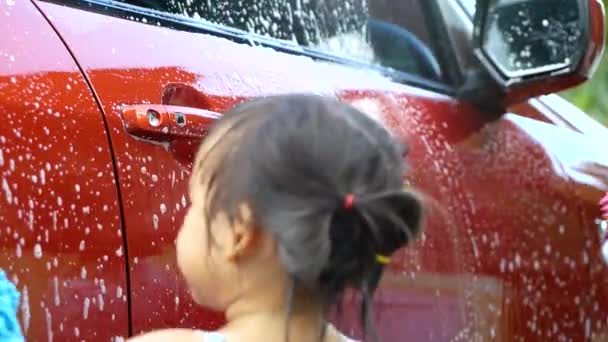 Cute sibling child girl helping her father washing car by mitt with bubbles soap outdoors. Car washing concept. - Footage, Video