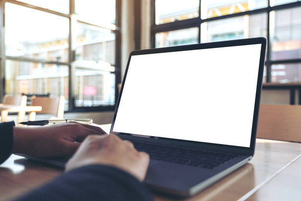 Mockup-Bild der Hände mit und Tippen auf Laptop mit leerem weißen Desktop-Bildschirm im Büro - Foto, Bild