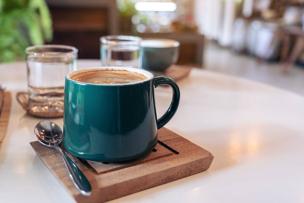 Closeup image of green mugs of hot coffee and glasses of water on table in cafe - Foto, Imagen