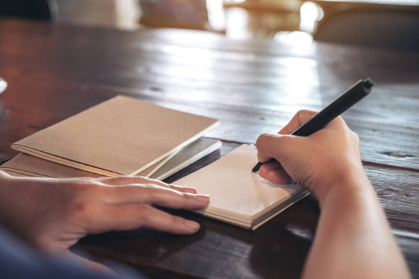 Imagem de close-up de uma mulher escrevendo em caderno em branco na mesa no café
 - Foto, Imagem