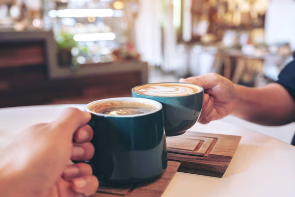 Close up image of a man and a woman clinking green coffee mugs in cafe - Photo, Image