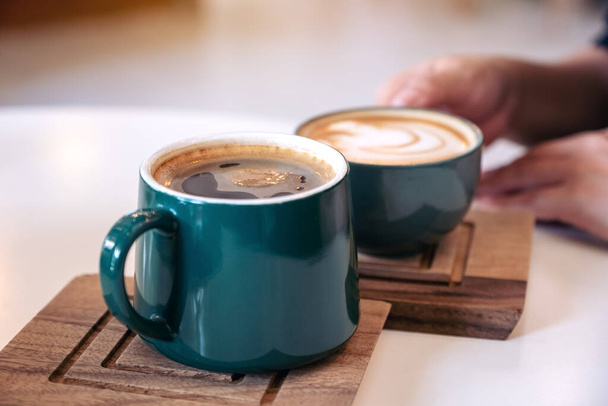 Close-up afbeelding van een hand met een groene koffie mokken in cafe - Foto, afbeelding