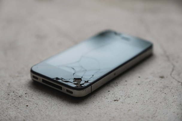 A cracked cell phone on the floor - Fotó, kép
