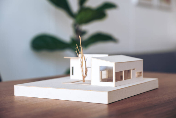 Архитектурная модель на деревянном столе в офисе с размытым природным фоном
 - Фото, изображение