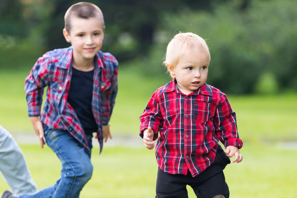 Twee speelse Kaukasische broer kinderen genieten van plezier samen spelen thuis backtard groen gras gazon op zomerdag. Broer gelukkige jeugd concept. - Foto, afbeelding
