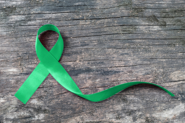 Πράσινη κορδέλα ευαισθητοποίησης συμβολικό τόξο για νεφρό, χοληδόχο κύστη, Bile Duct Καρκίνος, Γλαύκωμα, Λευχαιμία, Τραυματική Εγκεφαλική Βλάβη, και Ψυχική Υγεία ασθένεια (τόξο απομονώνονται σε παλαιωμένο ξύλο με περικοπή διαδρομή) - Φωτογραφία, εικόνα