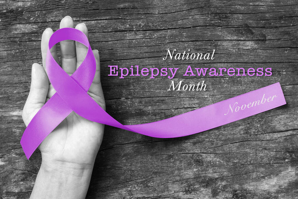 National Epilepsy Awareness Month in November by Levandulová stuha na ruce, zrající dřevěné pozadí  - Fotografie, Obrázek