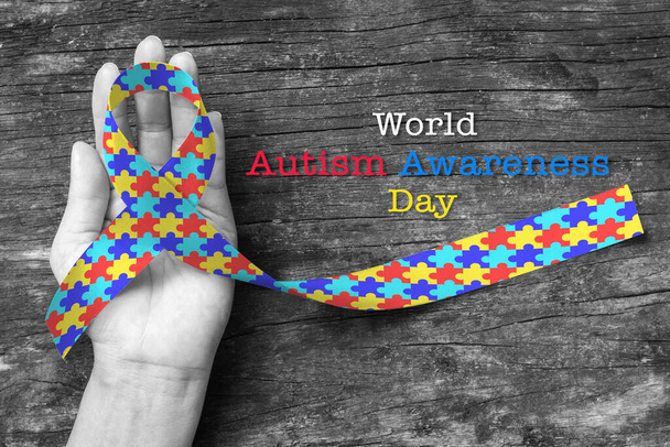Παγκόσμια ημέρα ευαισθητοποίησης του αυτισμού με την κορδέλα παζλ στο χέρι του ατόμου - Φωτογραφία, εικόνα