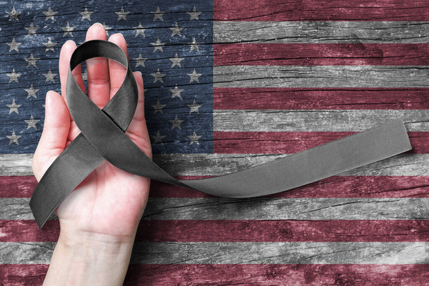 Estados Unidos Estados Unidos de América 9 / 11 memorial, Día del Patriota y el concepto del Día Nacional de Reconocimiento de prisioneros de guerra / MIA con cinta de conciencia negra en el apoyo de la mano de la gente en la bandera estadounidense  - Foto, imagen