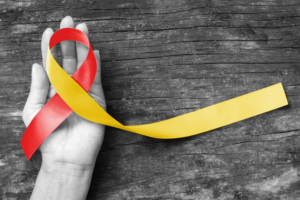 Dünya hepatit günü ve HIV / HCV ortak enfeksiyon farkındalığı kişinin el desteği ve eski ahşap üzerinde kırmızı sarı kurdele (kırpma yolu ile izole edilmiş) ile - Fotoğraf, Görsel