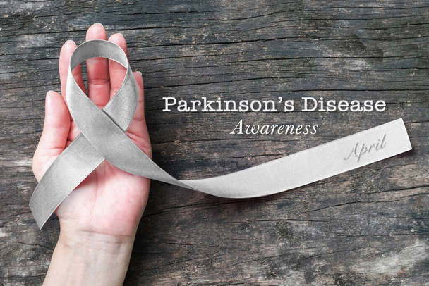 Zilverkleurig lint op de hand ondersteuning (geïsoleerd met clipping pad) voor de ziekte van Parkinson bewustzijn en hersentumor ziekte - Foto, afbeelding
