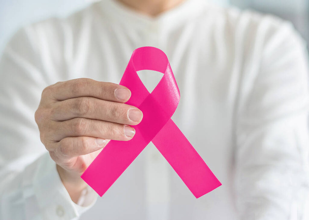 Göğüs kanseri farkındalığı için pembe kurdele ve Ekim ayında kadın tümör hastalıkları konulu kadın sağlık kampanyası konsepti ve saten yaylı el desteği  - Fotoğraf, Görsel