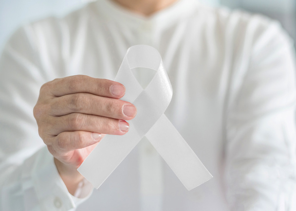 Weißes Band oder leichte Perlbogenfarbe symbolisch für die Sensibilisierung für Lungenkrebs, Knochenkrebs, Multiple Sklerose und Symbol für den internationalen Tag der Gewaltlosigkeit gegen Frauen - Foto, Bild