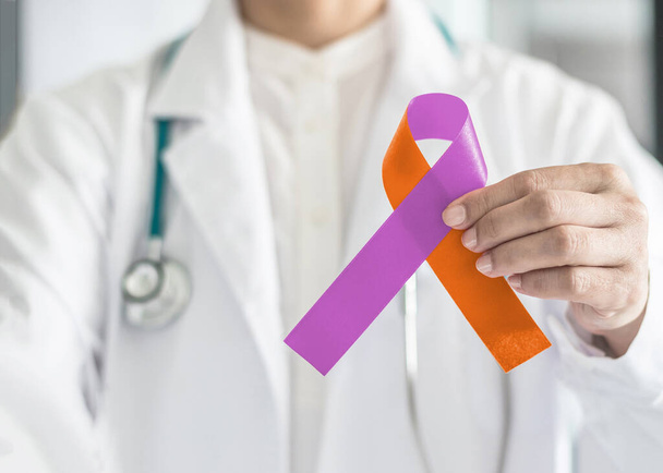 Enfermedad de psoriasis y eczema Dermatitis concepto de campaña de concienciación de la enfermedad de la piel con la cinta naranja púrpura orquídea color de lazo simbólico en el soporte de la mano del médico  - Foto, imagen