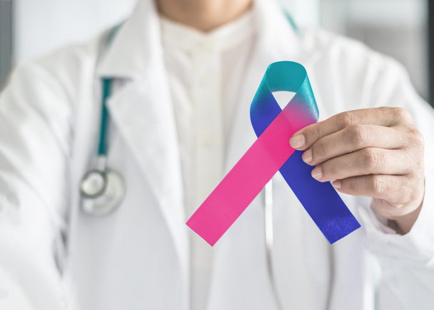 Ευαισθητοποίηση του καρκίνου του θυρεοειδούς σε Teal Pink Μπλε συμβολική πλώρη χρώμα στο χέρι του γιατρού για να υποστηρίξει τον ασθενή με νόσο του όγκου - Φωτογραφία, εικόνα