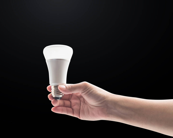 Concept d'économie d'énergie avec ampoule LED sur la main de la femme isolée sur fond noir avec chemin de coupe - Photo, image