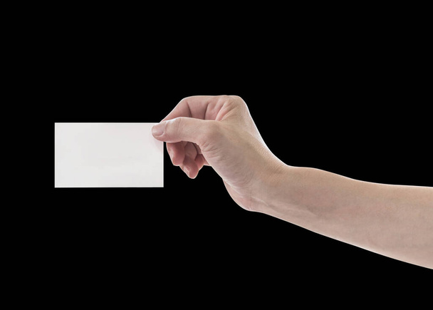 Mano sosteniendo plantilla de tarjeta de visita en blanco aislado sobre fondo negro con ruta de recorte (Mujer mano con luz de la llanta.)   - Foto, imagen