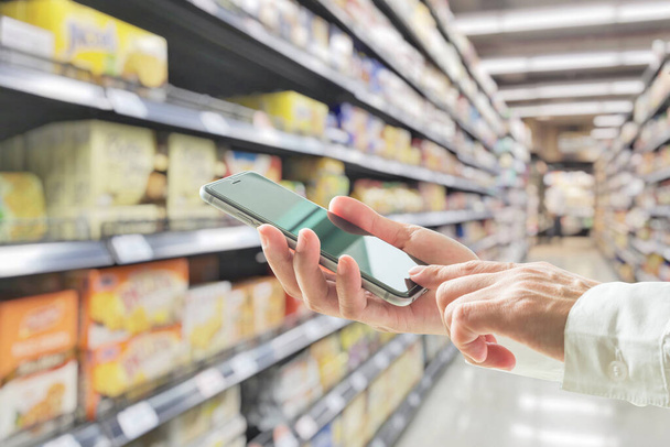Mode de vie numérique homme d'affaires ou acheteur utilisant le téléphone intelligent mobile pour les achats au détail dans les supermarchés  - Photo, image
