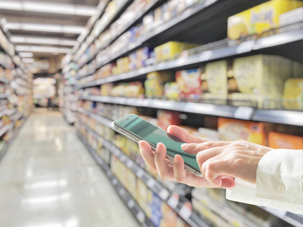 Цифровий спосіб життя бізнесмен або покупець, використовуючи мобільний смартфон для роздрібних покупок в супермаркеті
  - Фото, зображення