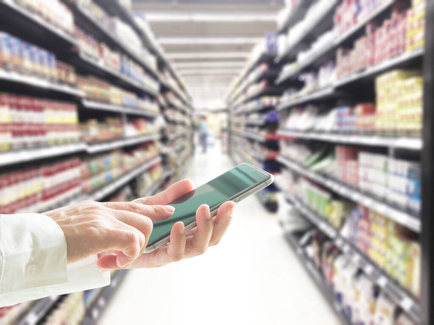 Cyfrowy styl życia osoba lub klient za pomocą smartfona komórkowego do zakupów detalicznych w supermarkecie  - Zdjęcie, obraz