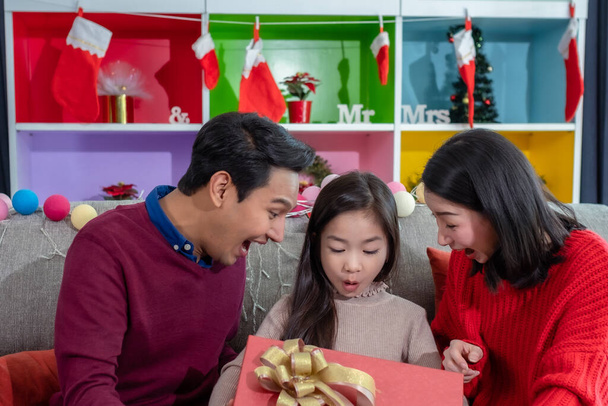 feliz asiática familia hija, padre, madre abrir gran regalo juntos y sorpresa en el día de Navidad en sala de estar que decorado con árbol de Navidad para el día del festival de Navidad
 - Foto, imagen