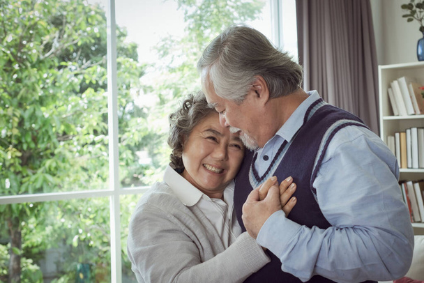 Gelukkig paar oude oudere senior man knuffelen vrouw en hand op hart en gelukkig met samen lachen thuis, pensionering en gezondheidszorg levensstijl en geliefde relatie concept - Foto, afbeelding
