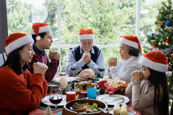 Famiglia asiatica fanno pregare prima di mangiare il giorno di Natale, sono felici e hanno pasto insieme - Foto, immagini