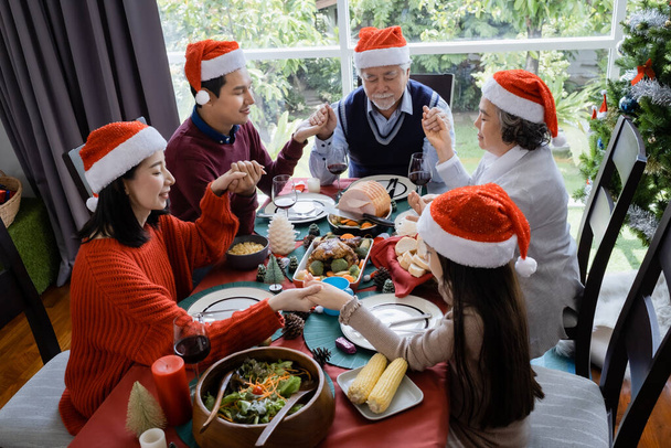 Asyalı aileler Noel günü yemek yemeden önce dua ederler, mutludurlar ve birlikte yemek yerler. - Fotoğraf, Görsel
