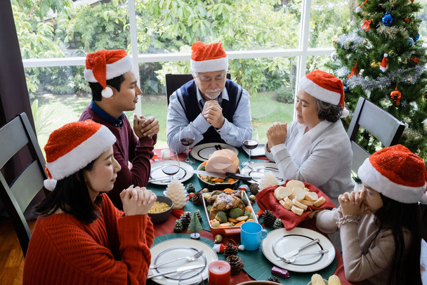 Asijské rodiny se modlí před jídlem na Štědrý den, jsou šťastní a mají společné jídlo - Fotografie, Obrázek