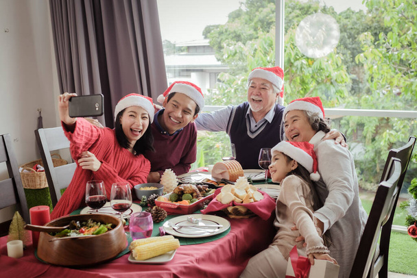 クリスマスの日の食事の後に一緒に大きな家族の自撮り、彼らは一緒に写真を撮る中で幸せと笑顔、アジアの家族の休日のコンセプト - 写真・画像