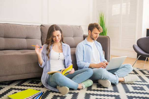 Young couple sitting on the floor studying together and looking involved - Photo, Image
