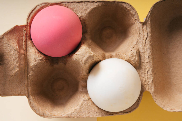 Vista dall'alto da vicino - Uovo rosa e uovo bianco in una scatola
. - Foto, immagini