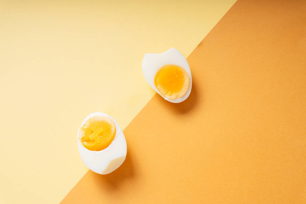 Πάνω άποψη - Βραστά αυγά φέτα πάνω από κίτρινο και καφέ φόντο. - Φωτογραφία, εικόνα