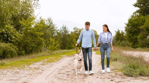 Excited couple and golden retriever walking in countryside - Fotoğraf, Görsel