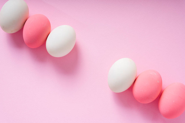 Top view - Group of white and pink eggs over pink background. - Foto, Imagen
