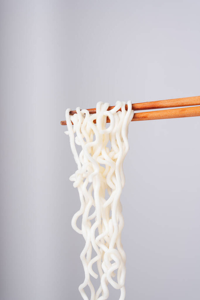 Sideview - eating instant noodle with wooden chopstick over white background. - Photo, Image