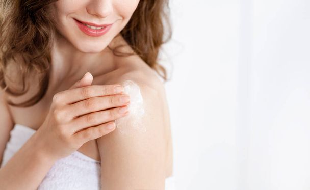 Cropped of young woman applying lotion on shoulder - Φωτογραφία, εικόνα