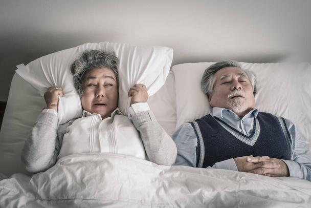 Yaşlı çift Kafkasyalı son sınıf kadın ve erkek yatakta uyur ve yatak odasında beyaz bir battaniye içinde horlarlar, aşk yaşam tarzı kavramına sahip emeklilik sağlık hizmetleri - Fotoğraf, Görsel
