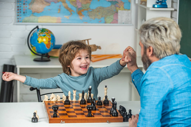 Young kid boy playing chess with father and having fun. Education and learning people concept - pupil and Teacher. - Foto, imagen