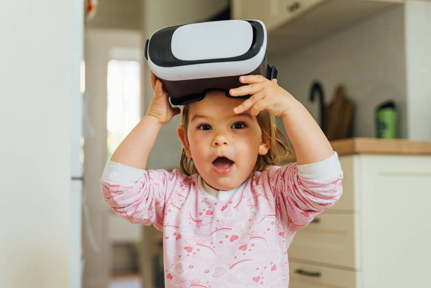 Toddler girl with vr glasses at home. Learning, watching movie, playing games. Future technologies - Фото, зображення