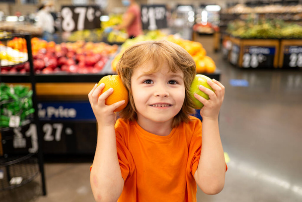 Healthy food for young family with kids. Portrait of funny little child holding shopping bag full of fresh vegetables. A boy is shopping in a supermarket. - Foto, immagini