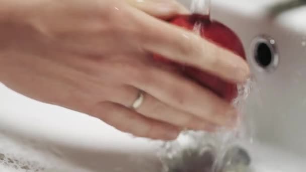 Closeup of hands washing a red Apple under running water. Healthy and clean food - Materiaali, video