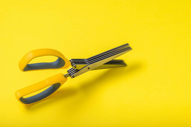 Scissors with five blades on a yellow background. - Foto, afbeelding