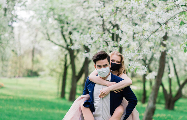 Young loving brides in park with medical masks during quarantine on their wedding day. Coronavirus, disease, protection, sick, illness flu europe celebration canceled, pandemic - Zdjęcie, obraz