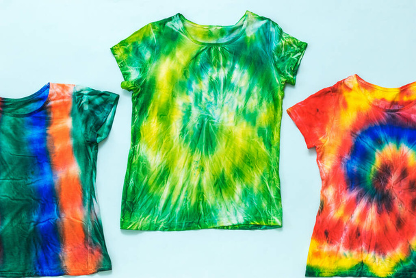 Set van t-shirts gedecoreerd in tie dye stijl op een lichte achtergrond. Vlakke plaat. - Foto, afbeelding