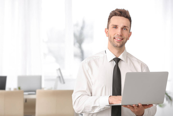Портрет гарного бізнесмена з ноутбуком в офісі
 - Фото, зображення