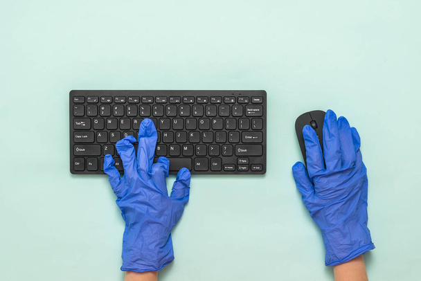 Hände in blauen medizinischen Handschuhen arbeiten an einer drahtlosen Tastatur. - Foto, Bild